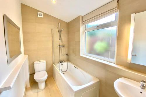 a bathroom with a toilet and a sink and a window at Cleveland House - Perfect for Beaches and Town. in Bournemouth