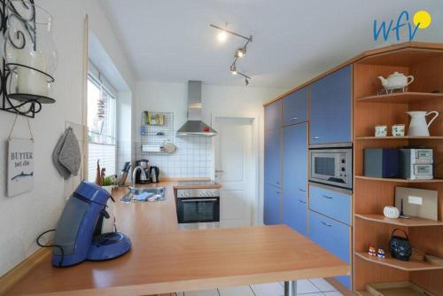 a kitchen with blue cabinets and a wooden table at Ferienhaus Seepferdchen in Borkum