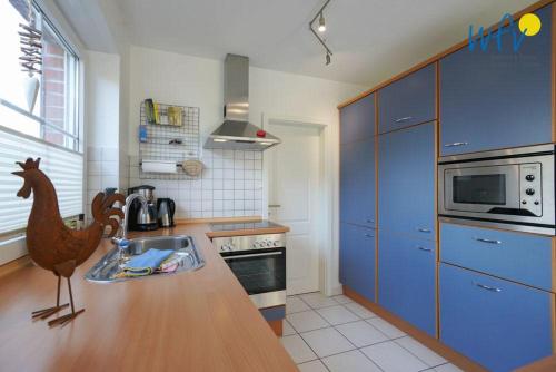 a kitchen with blue cabinets and a chicken statue in it at Ferienhaus Seepferdchen in Borkum