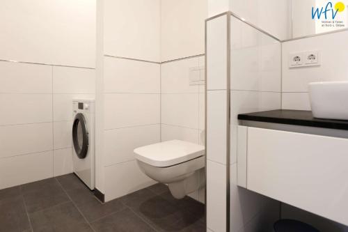 a white bathroom with a toilet and a sink at Haus Talita - Wohnung DELTA in Juist