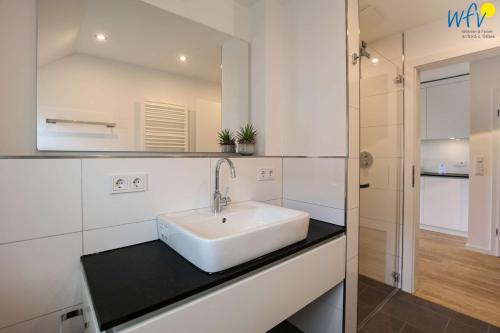 a bathroom with a white sink and a mirror at Haus Talita - Wohnung ZULU in Juist
