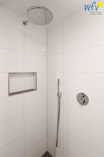 a bathroom with a shower with white tiles at Haus Talita - Wohnung LIMA in Juist