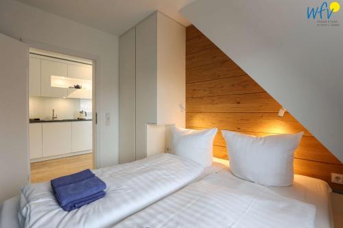 a bedroom with a white bed with a wooden headboard at Haus Talita - Wohnung GOLF in Juist