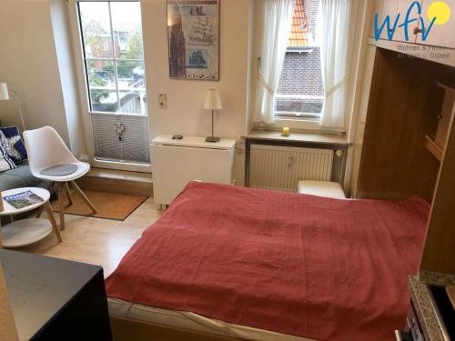 a small bedroom with a bed and two windows at Haus Solaris - Ferienwohnung Lüttje Koje in Wangerooge