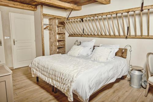 een slaapkamer met een groot bed met witte lakens bij Le Pas De Moineau in Lhuis