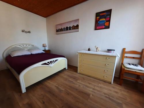 une chambre avec un lit, une commode et une chaise dans l'établissement Appartement Vue Sur Mer, à Les Sables-dʼOlonne