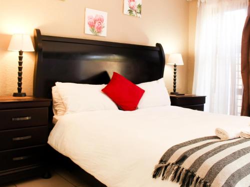 a bedroom with a white bed with red pillows at Dumelang Executive Lodge- OFF-GRID Solar powered Midrand in Midrand