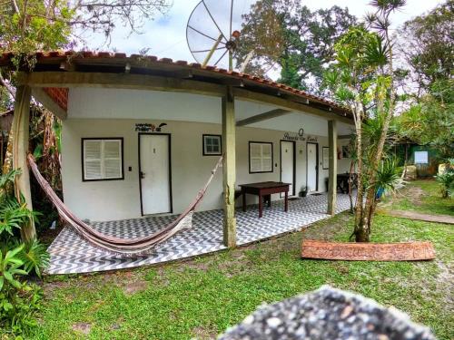 a house with a hammock in the yard at Pousada Recanto da Gruta in Ilha do Mel