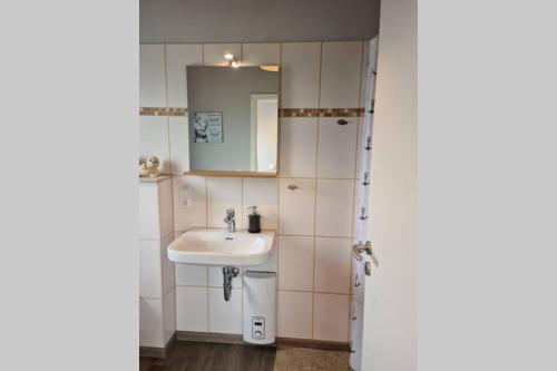 La salle de bains est pourvue d'un lavabo et d'un miroir. dans l'établissement Ferienhaus Haus Seehund direkt hinterm Deich an der Nordsee, à Schweiburg