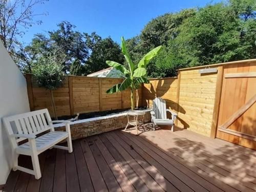 two chairs and a palm tree on a wooden deck at Chambre Cosy Chic in Challans