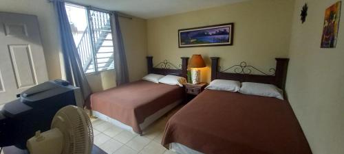 Habitación de hotel con 2 camas y ventana en Hostal Los Volcanes en Guatemala