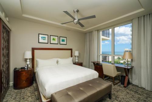 a bedroom with a bed and a desk and a window at Palm Beach Singer Island Resort & Spa Luxury Suites in Riviera Beach