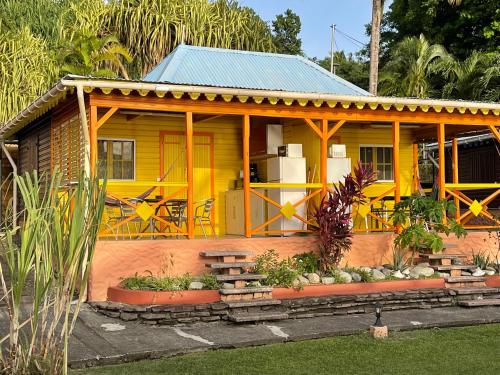 a small yellow house with a porch and some plants at Le Nid Tropical in Bouillante