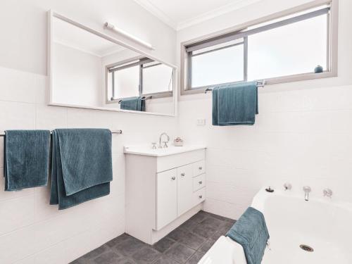 een badkamer met een bad, een wastafel en een spiegel bij The Grey Havens in Evans Head