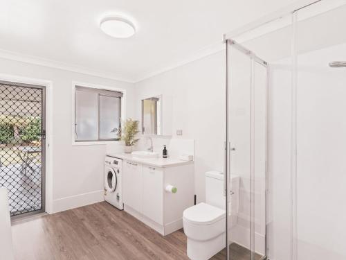 a white bathroom with a toilet and a sink at The Grey Havens - 58 Cypress Street in Evans Head