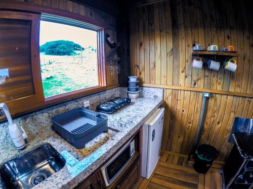a kitchen with a counter with a sink and a window at Hotel Guerra - Pousada Montebelo in Jaguaruna