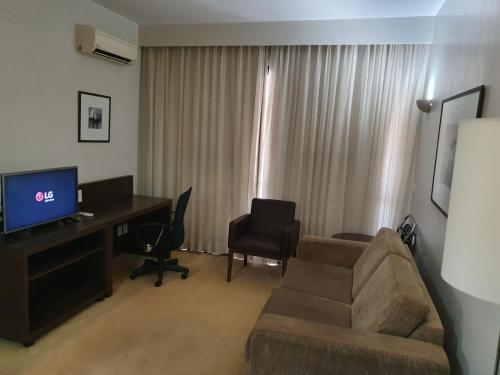 sala de estar con sofá y escritorio con ordenador en Bonaparte Hotel Flat Particular en Brasilia
