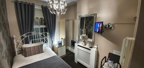 1 dormitorio con cama, espejo y lámpara de araña en Beechwood Guest House, en South Shields