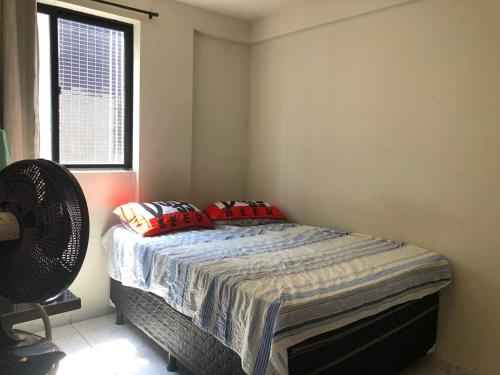 um quarto com uma cama com almofadas vermelhas e uma janela em Bessa João Cabral a 50 metros da praia em João Pessoa
