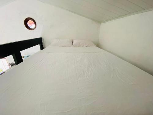a large white bed in a small room at A Piece of Paradise in San Carlos