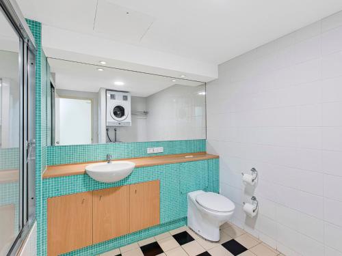 a bathroom with a toilet and a sink and a mirror at Waterfront Apartment 216 in The Entrance