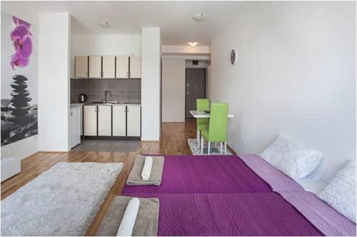a living room with a large purple bed and a kitchen at Modern Living Apartments in Skopje