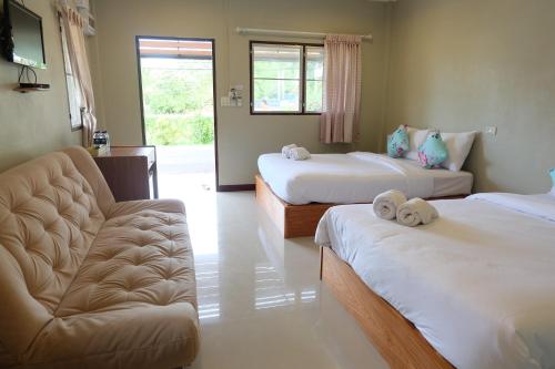 a hotel room with two beds and a couch at Baansuanchan resort in Ban Tha Nam Tun