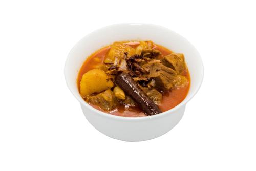 a white bowl of soup with meat and vegetables at New Siam II in Bangkok