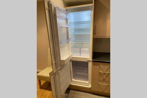 an empty refrigerator with its door open in a kitchen at Luxurious & Cosy Apartment in Surrey in Weybridge