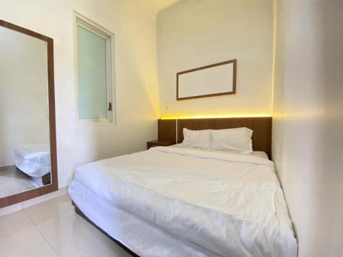 1 dormitorio con cama blanca y espejo en ANA INN Ambarawa Mitra RedDoorz, en Semarang