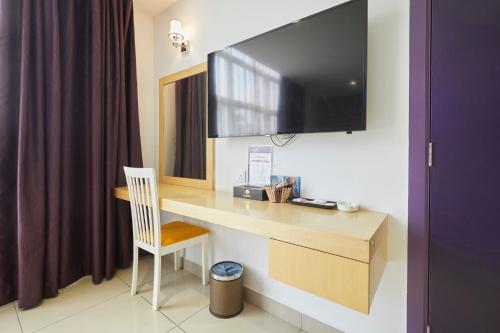 a room with a desk with a television on the wall at East Sun Hotel Sekinchan Self Check In in Sekincan