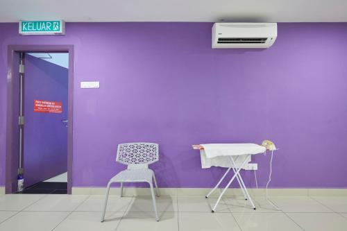 a purple wall with two chairs and a heater at East Sun Hotel Sekinchan Self Check In in Sekincan
