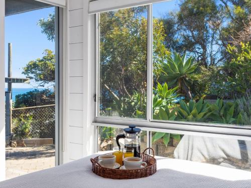 a breakfast table with a basket of coffee and orange juice at Coorumbene 8 Scenic Way in Normanville