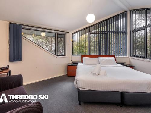 a bedroom with a bed and large windows at Kirkwood 4 in Thredbo