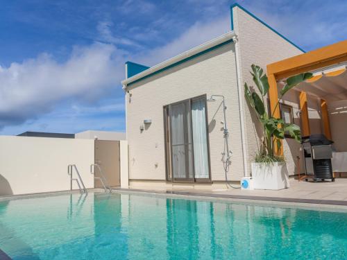 a house with a swimming pool next to a building at 美ら海ビレッジ プール＆テラス in Motobu