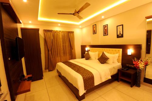 a bedroom with a bed and a television in it at MC Suites Mysuru in Mysore