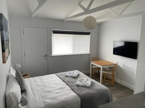 a bedroom with a bed and a table and a television at Robe Nampara Cottages in Robe