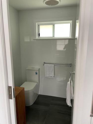 a white bathroom with a toilet and a window at Robe Nampara Cottages in Robe