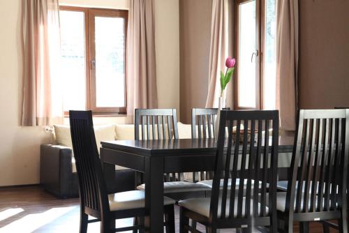 a dining room table with four chairs and a vase with a flower at Двете къщи в планината in Beli Osŭm