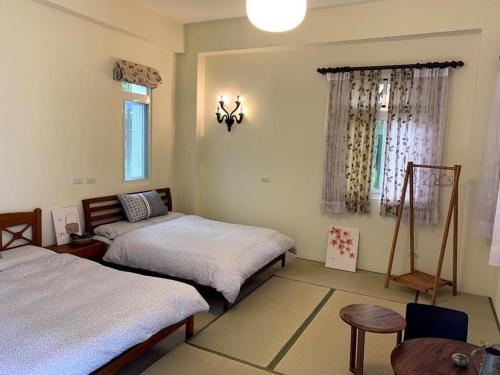 een slaapkamer met 2 bedden, een tafel en een raam bij 發呆永安 in Yung-an-ts'un