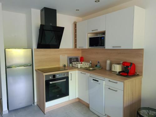La cuisine est équipée de placards blancs, d'une cuisinière et d'un réfrigérateur. dans l'établissement Renovated apartment, air-conditioned 5min from sea, à Saint-Raphaël