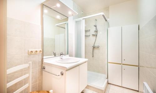 ein weißes Bad mit einem Waschbecken und einer Dusche in der Unterkunft Calidris 101 incl garage in Koksijde