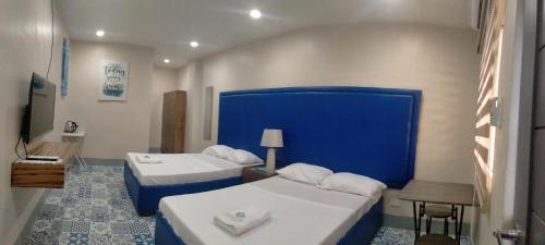 een hotelkamer met 2 bedden en een blauwe muur bij Athena's Guest House in Tacloban