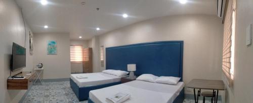1 dormitorio con 2 camas y pared azul en Athena's Guest House, en Tacloban