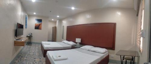 een hotelkamer met 2 bedden en een televisie bij Athena's Guest House in Tacloban