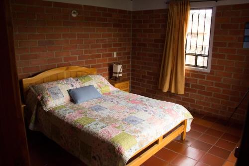 a bed in a bedroom with a brick wall at Cabaña Campestre El Refugio in Paipa
