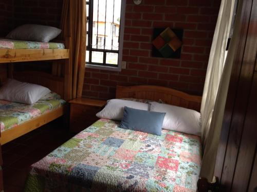 a bedroom with two beds in a brick wall at Cabaña Campestre El Refugio in Paipa