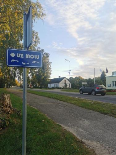 a blue street sign on the side of a road at Kalvāni in Mērsrags