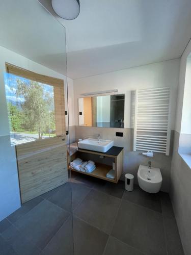a bathroom with a sink and a toilet and a mirror at Appartments Lindenhof in Riscone