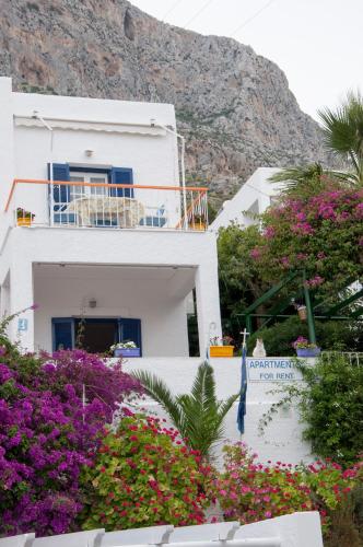 a white house with flowers in front of a mountain at Tatsis Apartments in Masouri